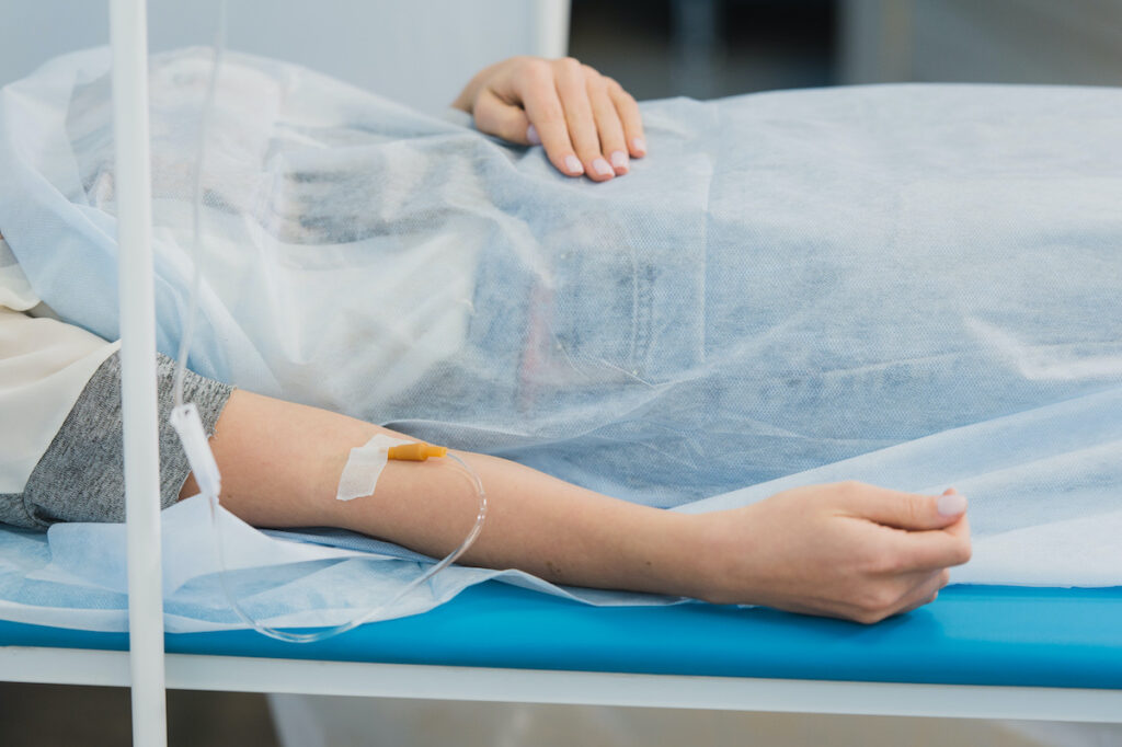 Patient hand with IV drop and patient tag.