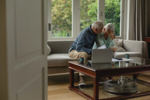 Side view of active senior Caucasian couple calculating bills and feel too sad in living room at home