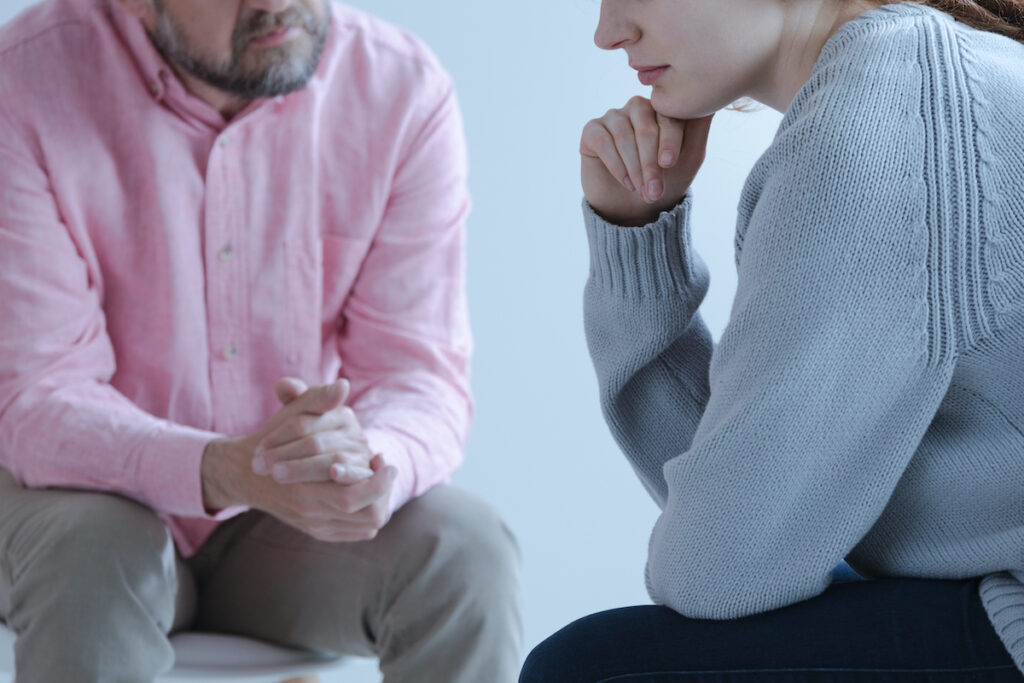 Close-up of a young sad woman sharing her grief with a psychothe