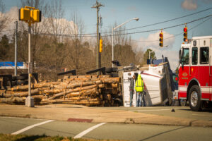 Overturned logging truck with work men and fire engine