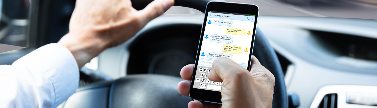 Close-up Of A Man's Hand Typing Text Message On Mobile Phone While Driving Car