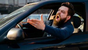 Bearded young man road raging , yelling from the car closeup shot