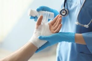 Medical assistant applying bandage onto patient's hand in clinic, closeup